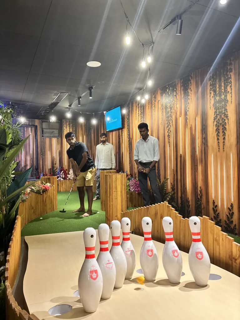 A player putting towards a hole lined with bowling pins at Putt House