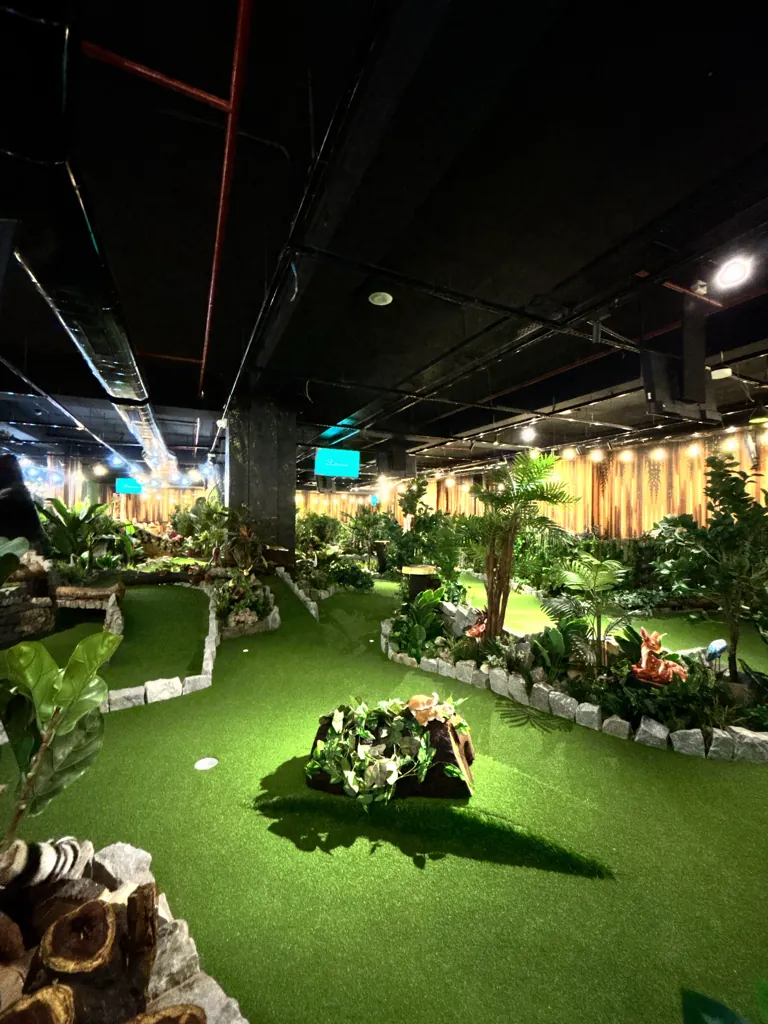Palms, ferns and lights along the jungle-themed mini golf course at Putt House Ahmedabad